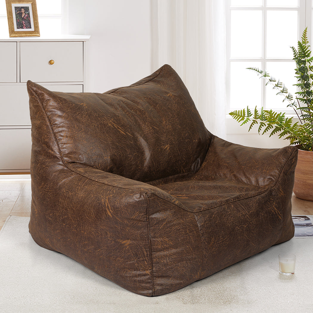 Brown leather bean bag chair in a room with a window and plant.